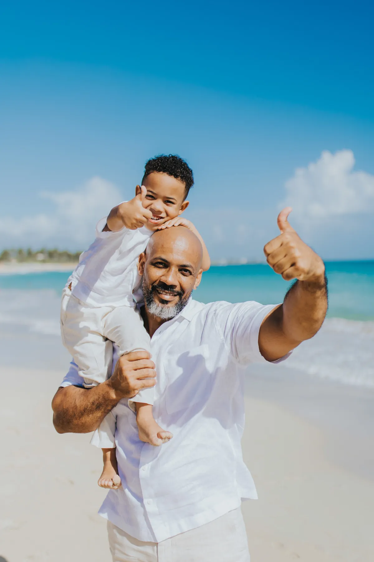 Dad and son giving thumbs up on the beach