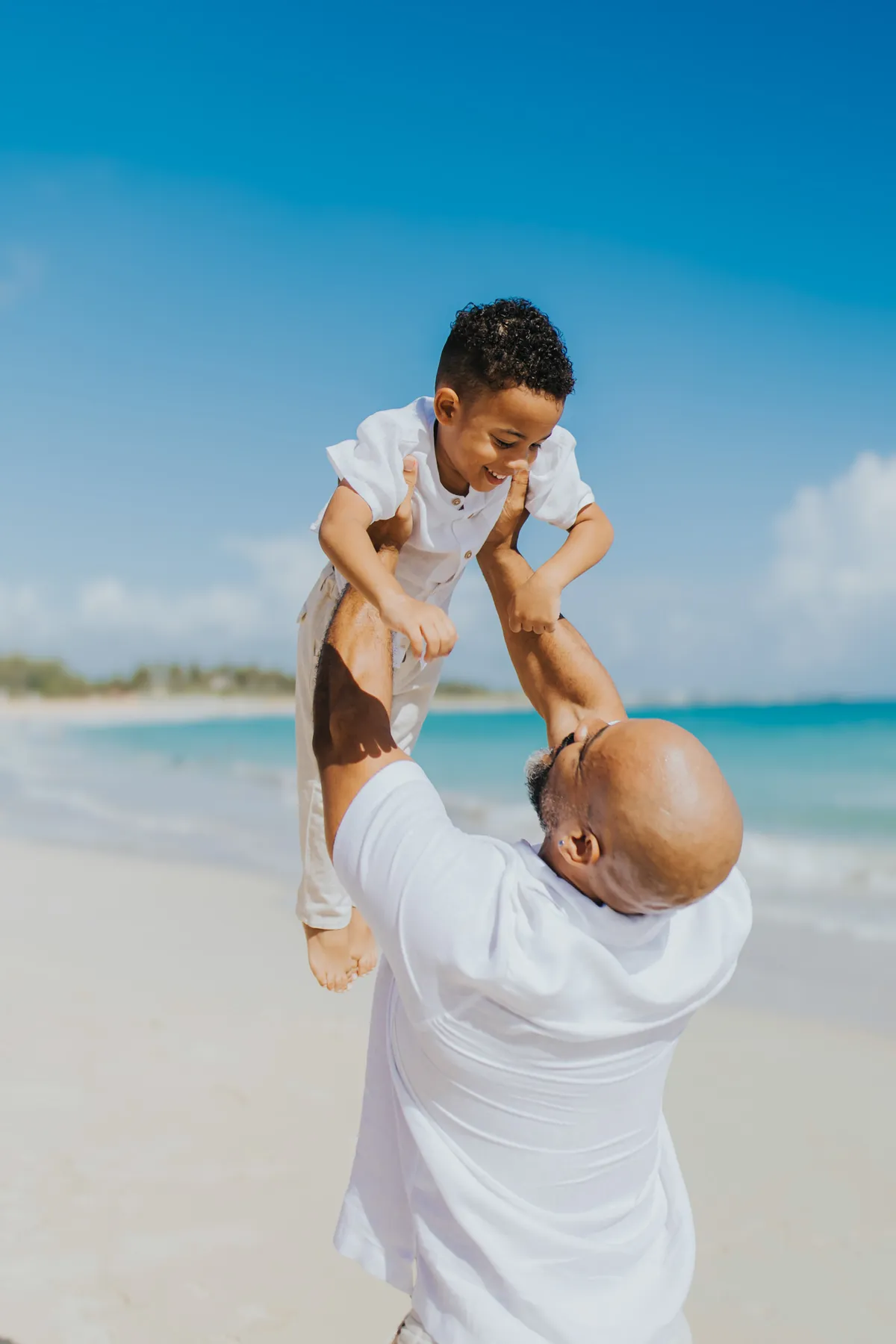 Boy flying in his father's arms by the sea