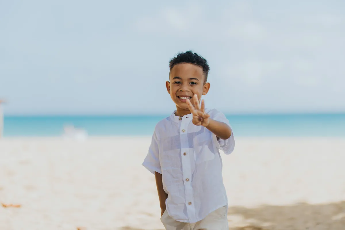 Boy showing three fingers with a big smile