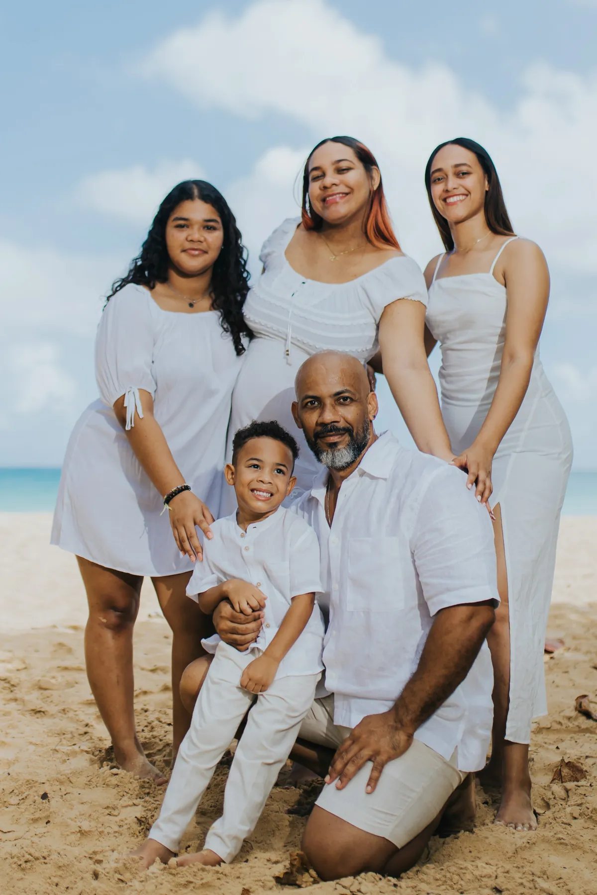 The whole family together on the sand, dad kneeling with his son