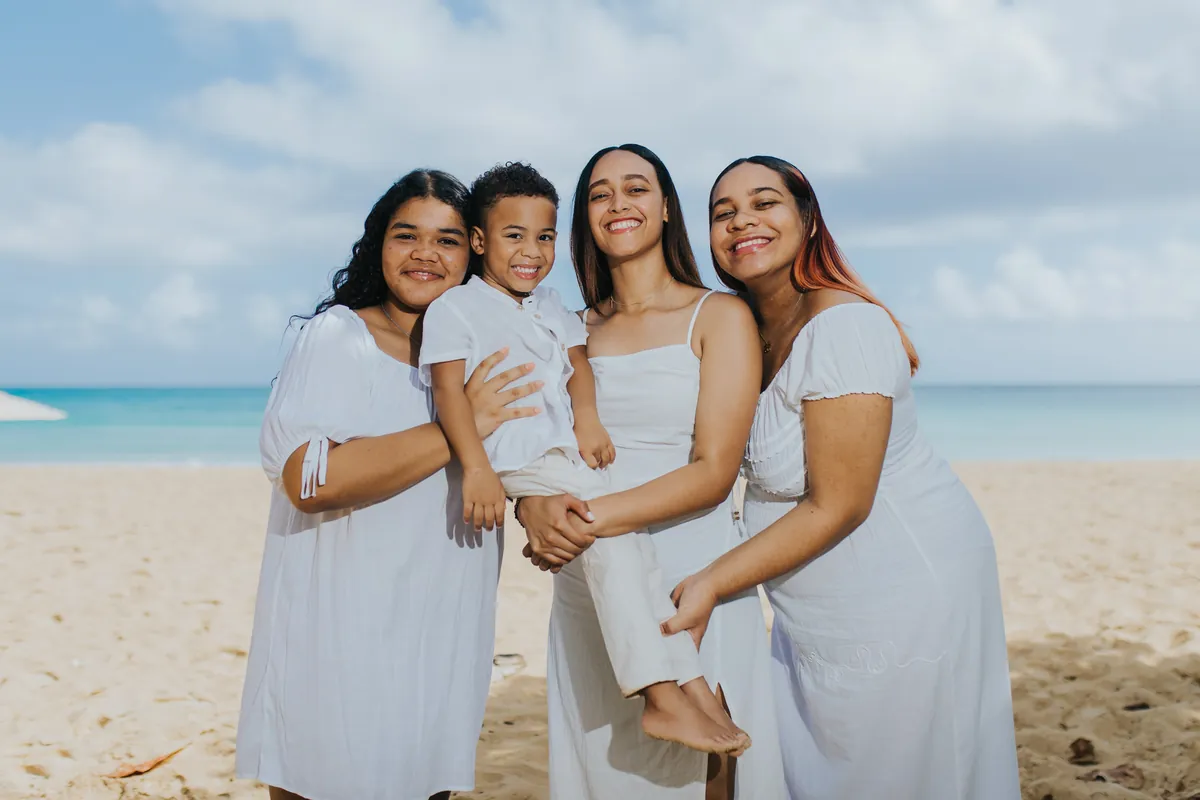 Three sisters holding their little brother, turquoise sea behind