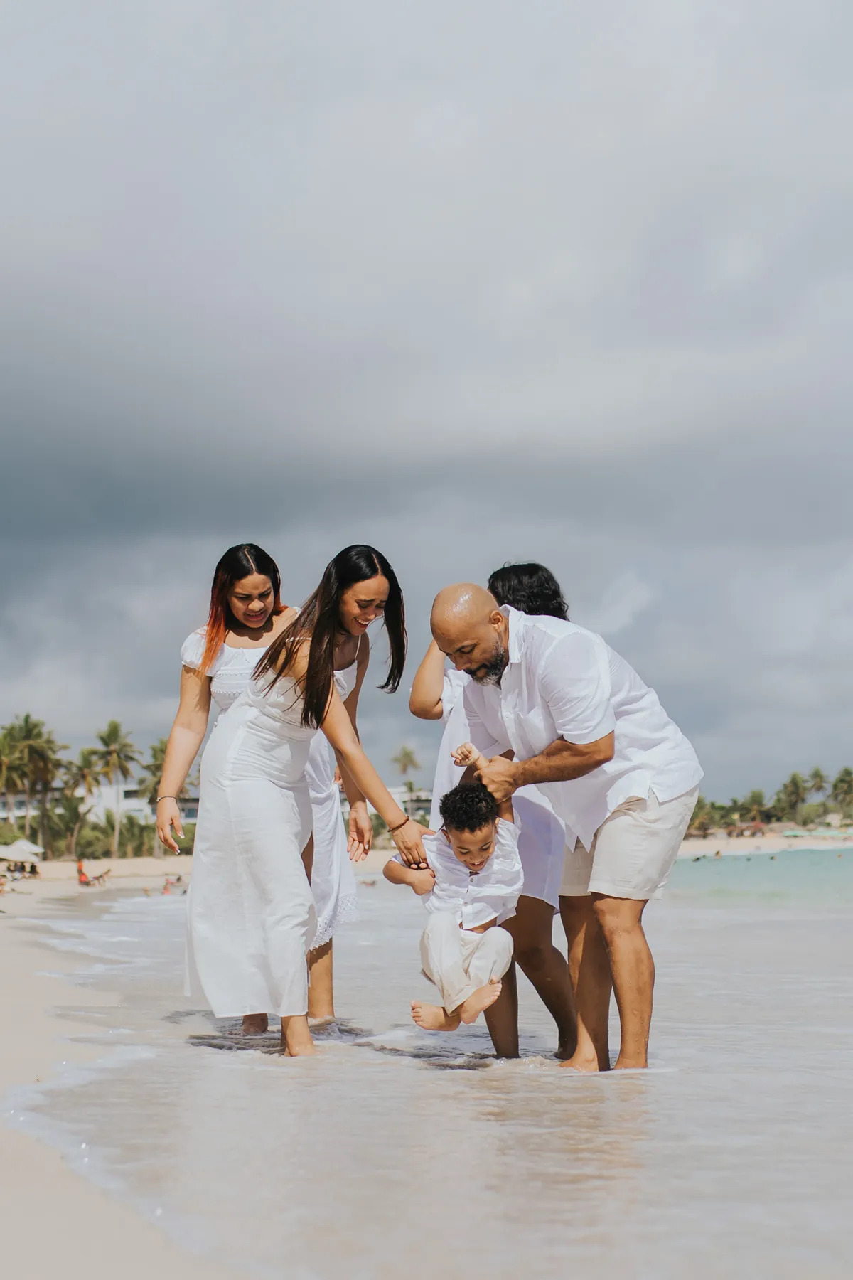 Dad swinging his son over the waves while the family laughs