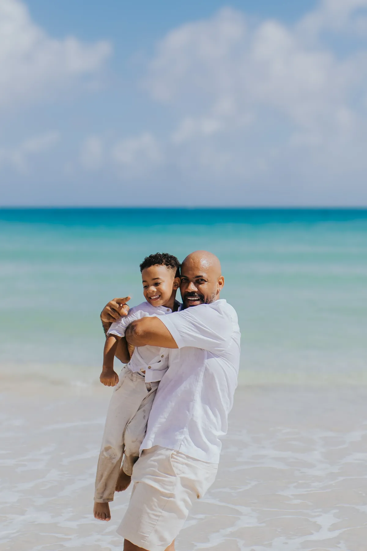 Dad spinning his son in the shallow turquoise water