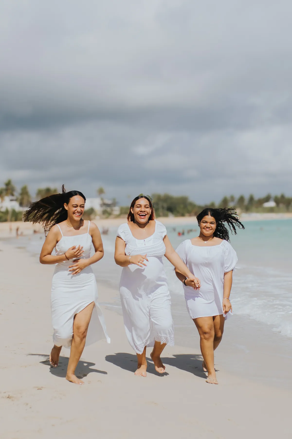 Mom and daughters running along the shore, hair in the wind