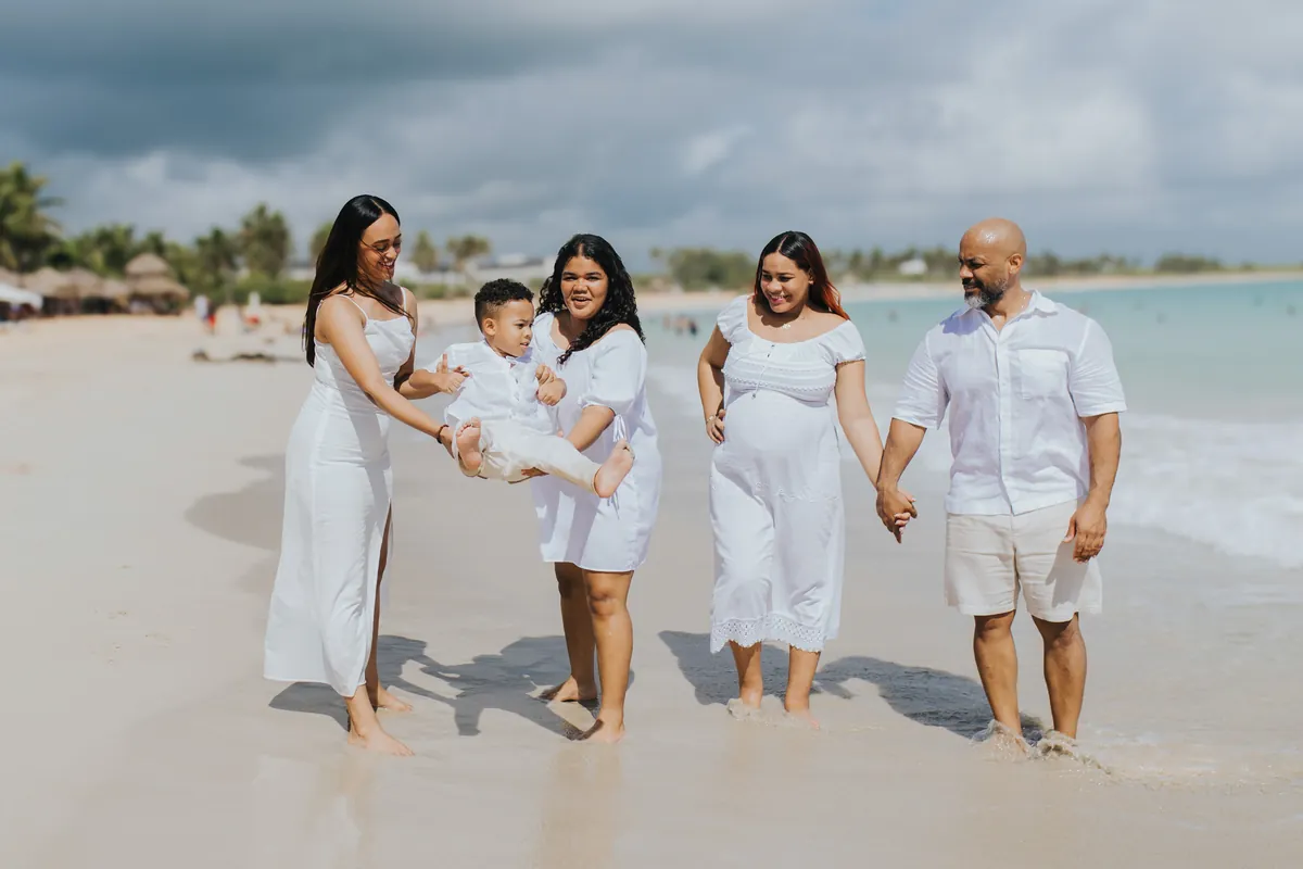 The whole family walking in the shallow water, the boy lifted between them
