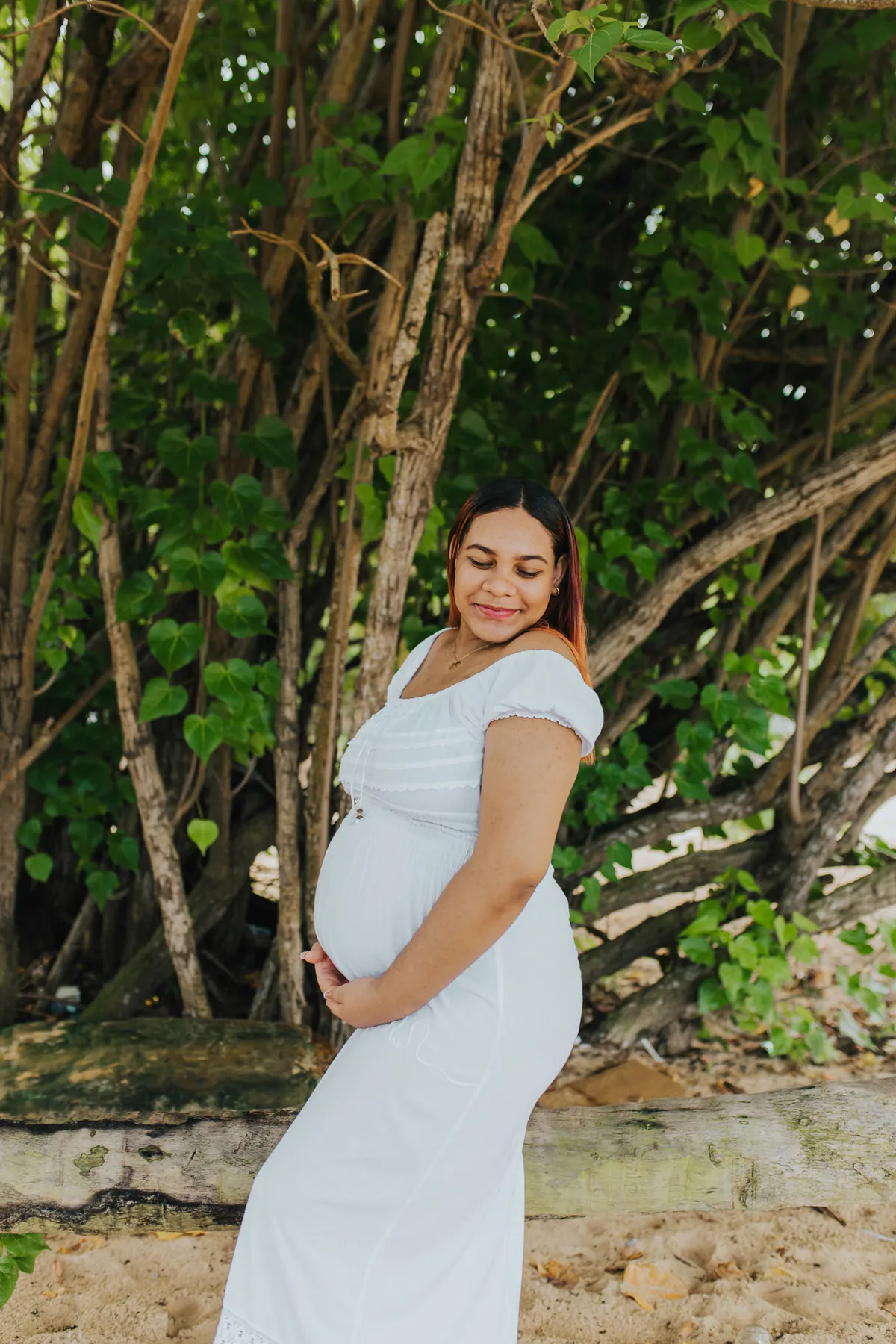 Mom-to-be looking down at her belly, eyes closed