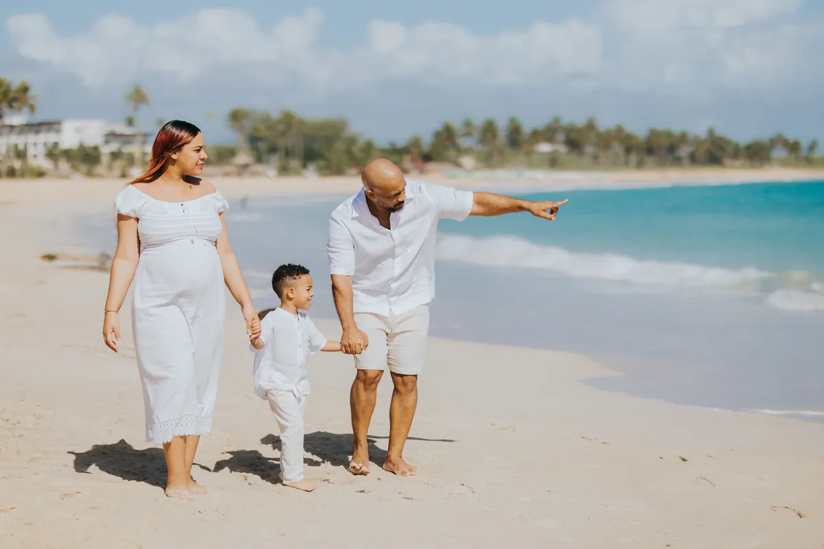Expecting mom walking with her family, dad pointing at the sea