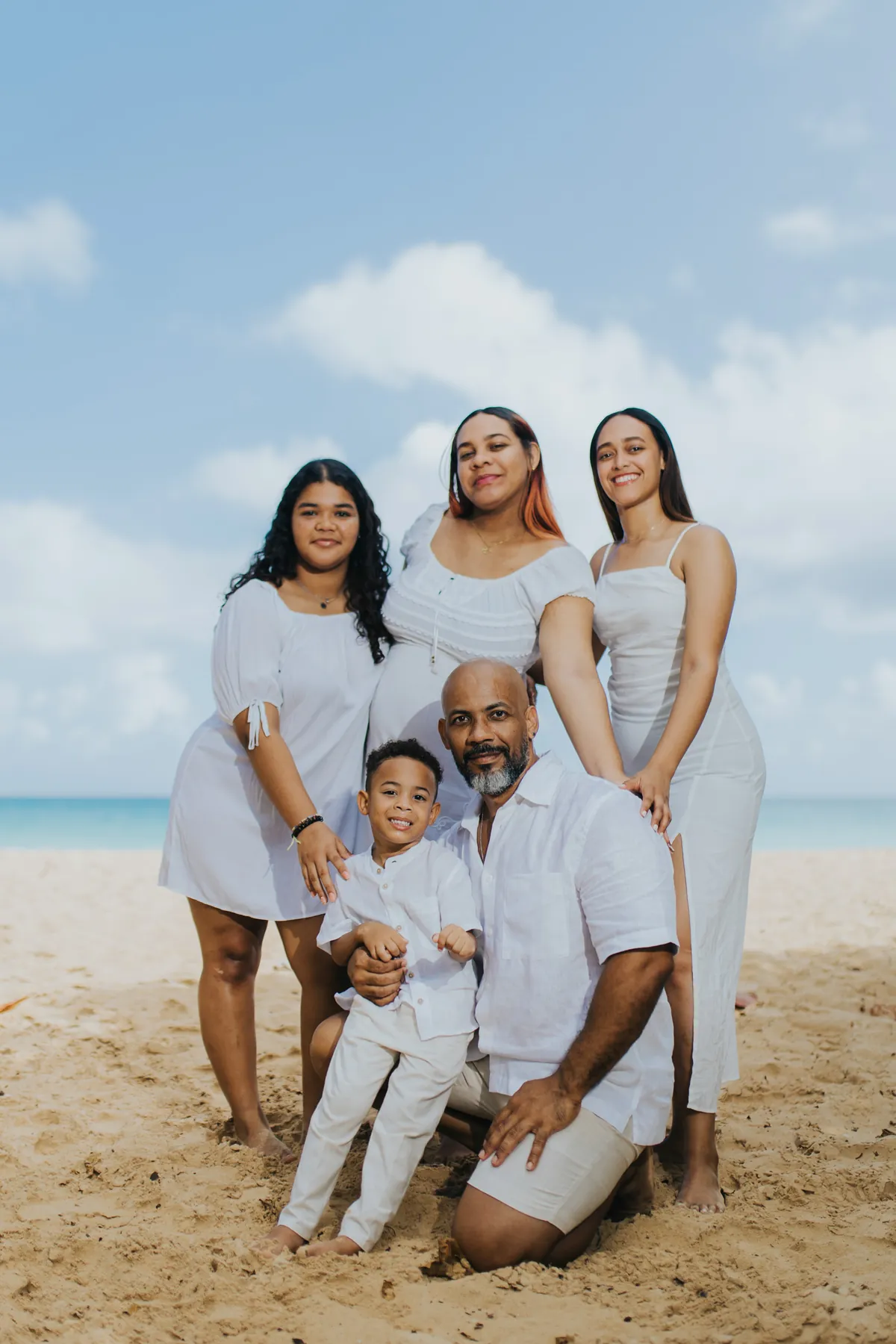 Mom-to-be with her whole family on the sand, dad kneeling