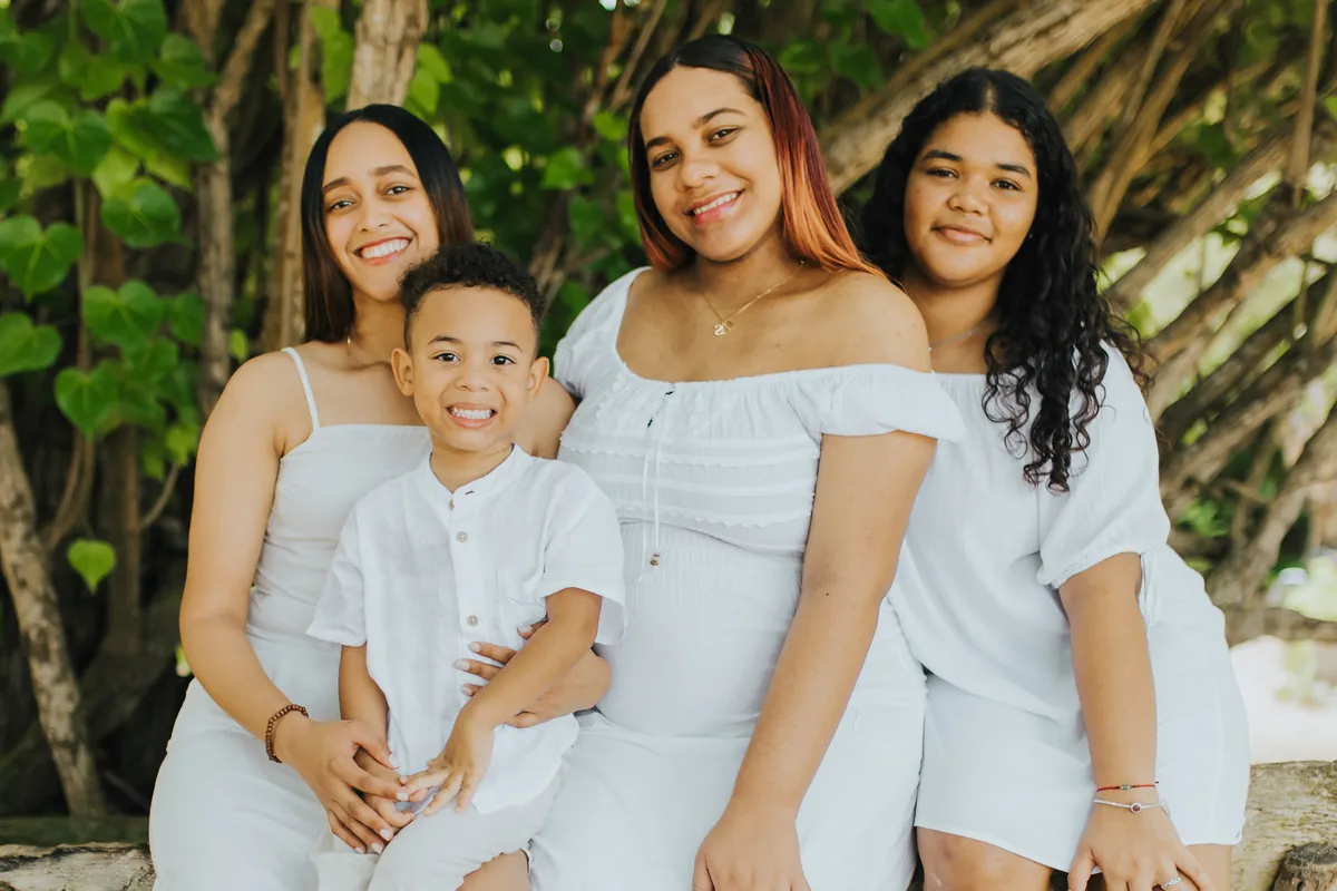 The mom-to-be with her daughters and son in the shade of the trees