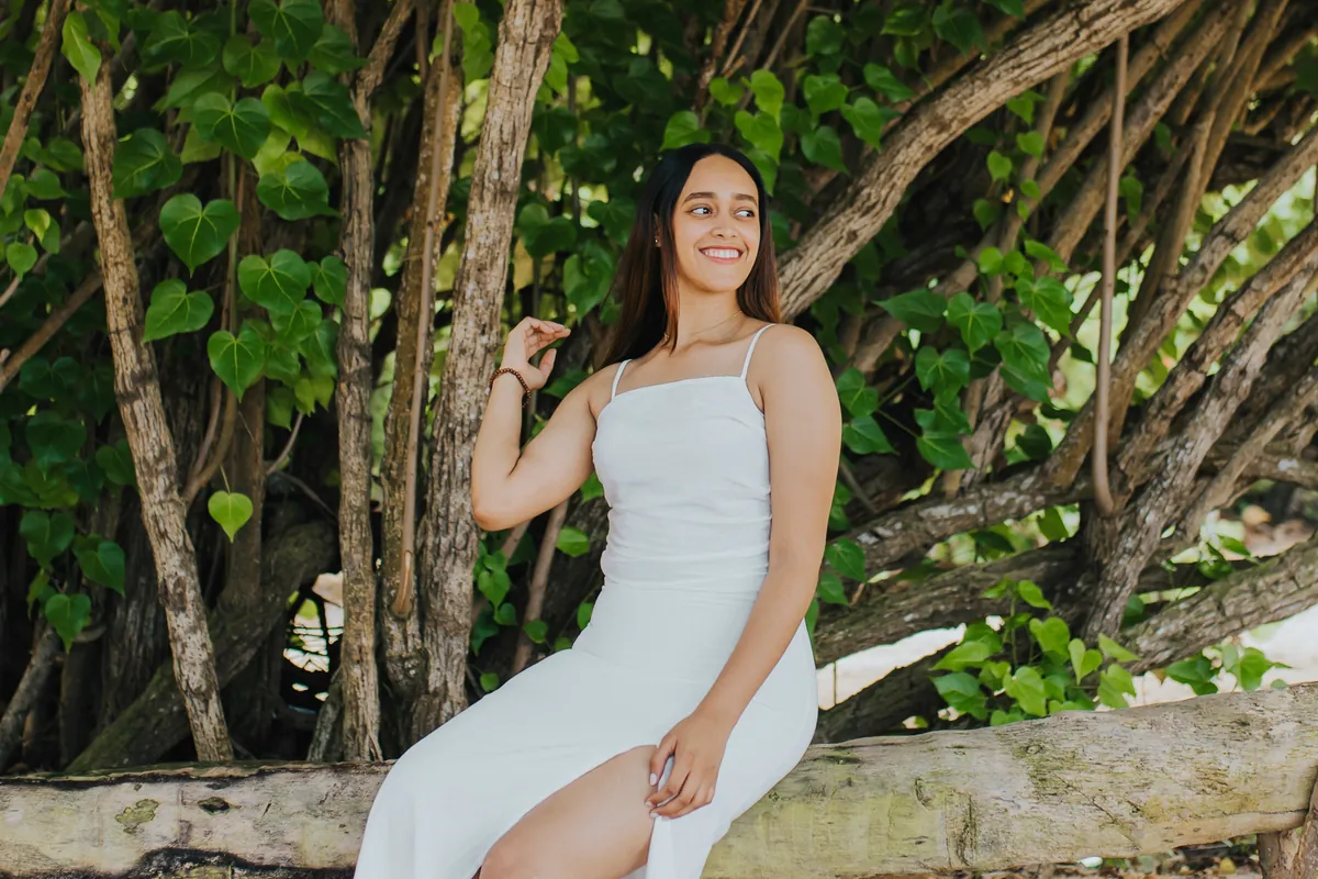 Smiling young woman with the trees behind her