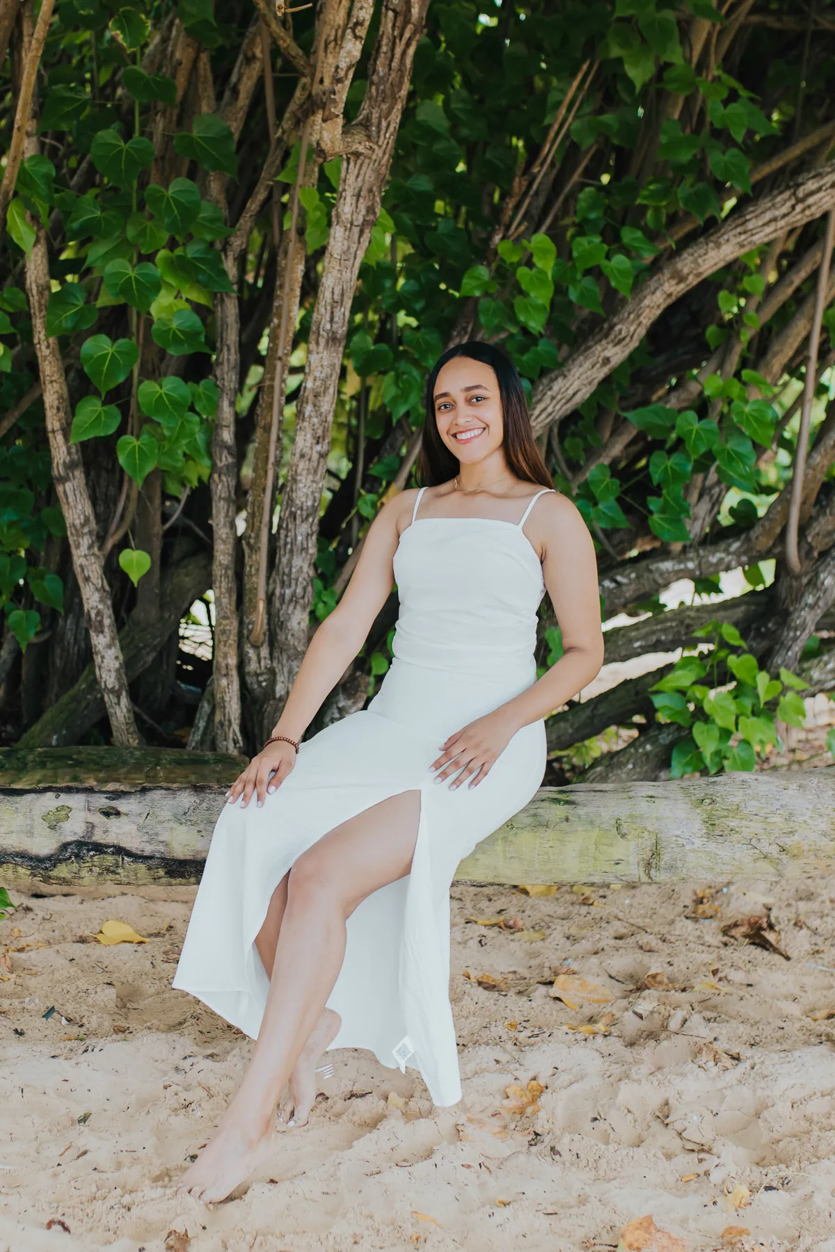 Relaxed portrait on driftwood, bare feet in the sand