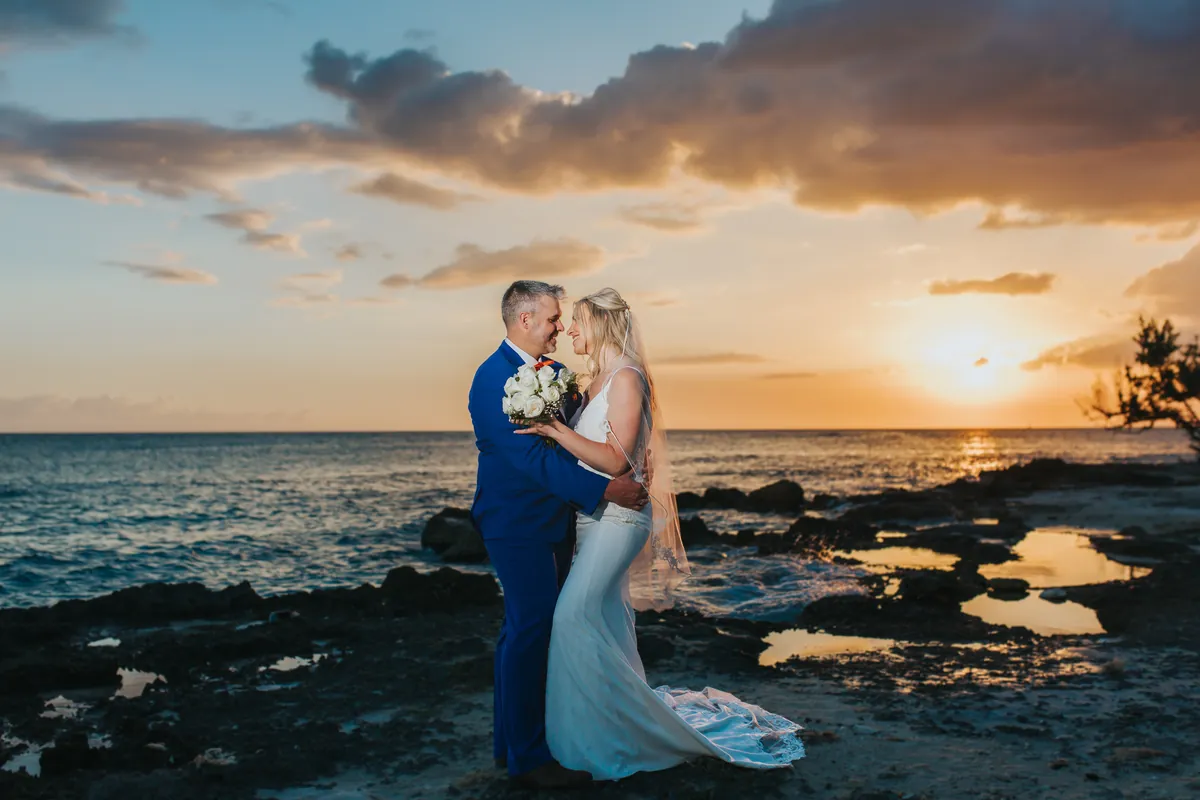 Bride and groom embracing at sunset on the rocky Punta Cana coast