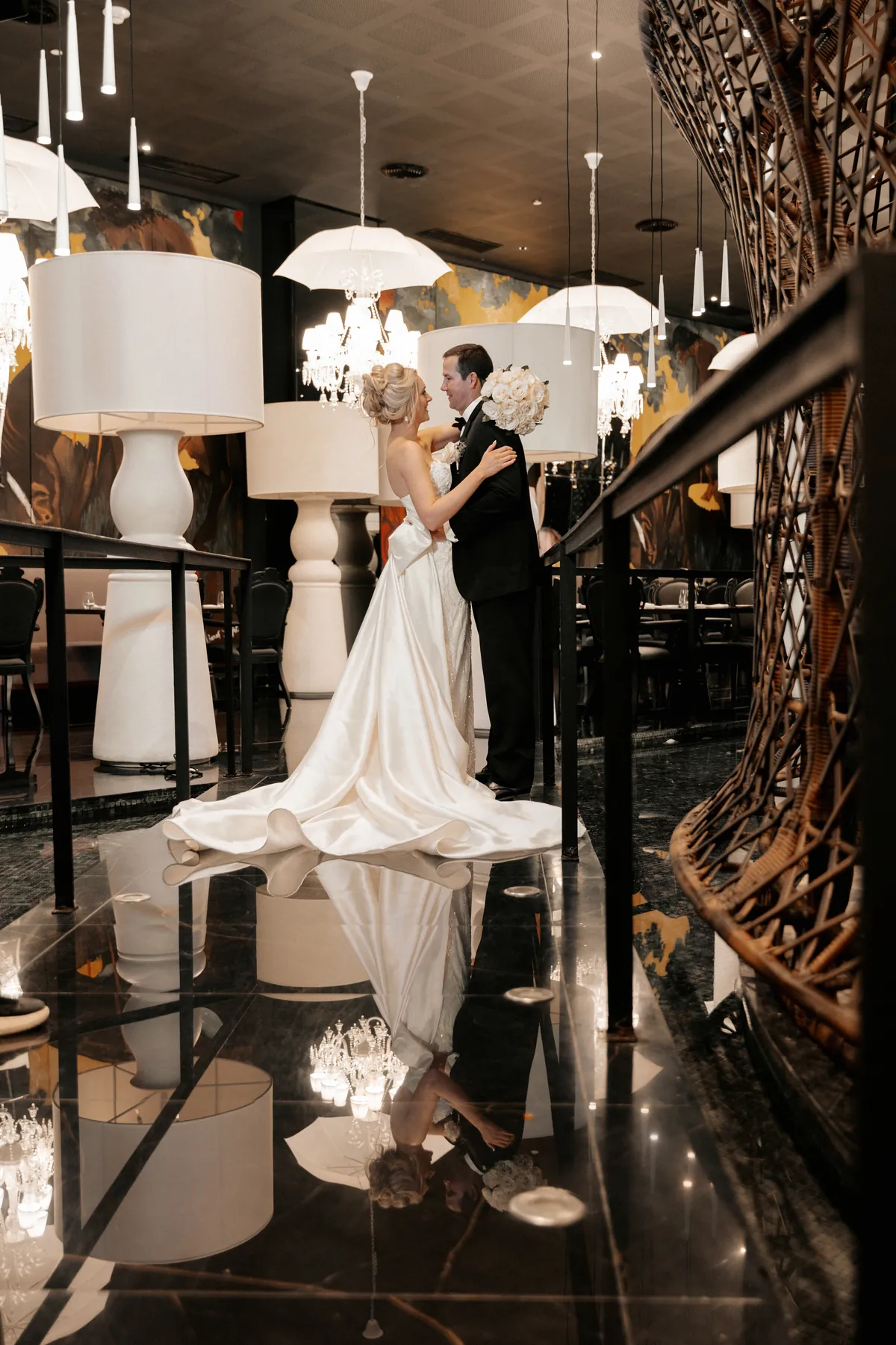 Newlyweds embracing in a resort restaurant, reflected on the black marble floor