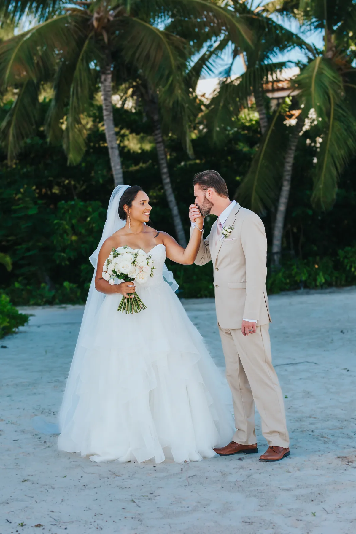 Groom kissing the bride's hand on the beach