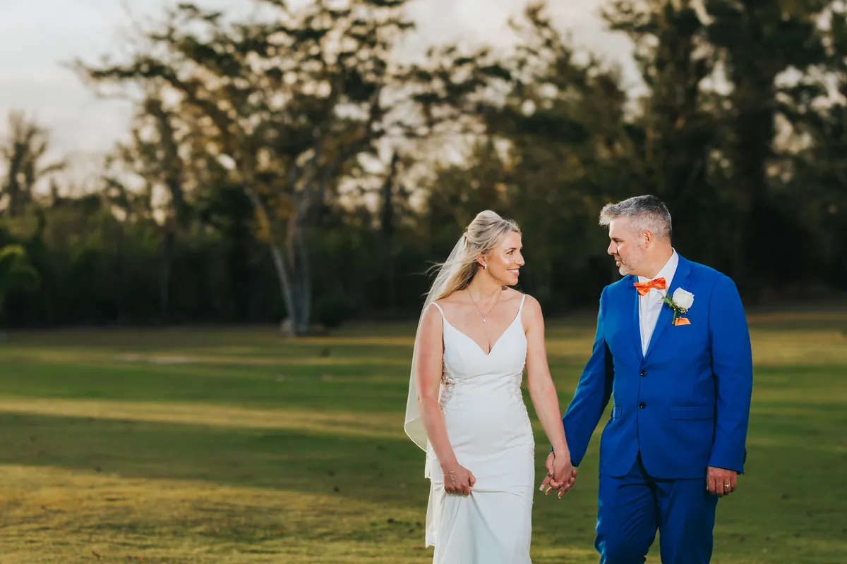 Newlyweds walking across a lawn in golden light