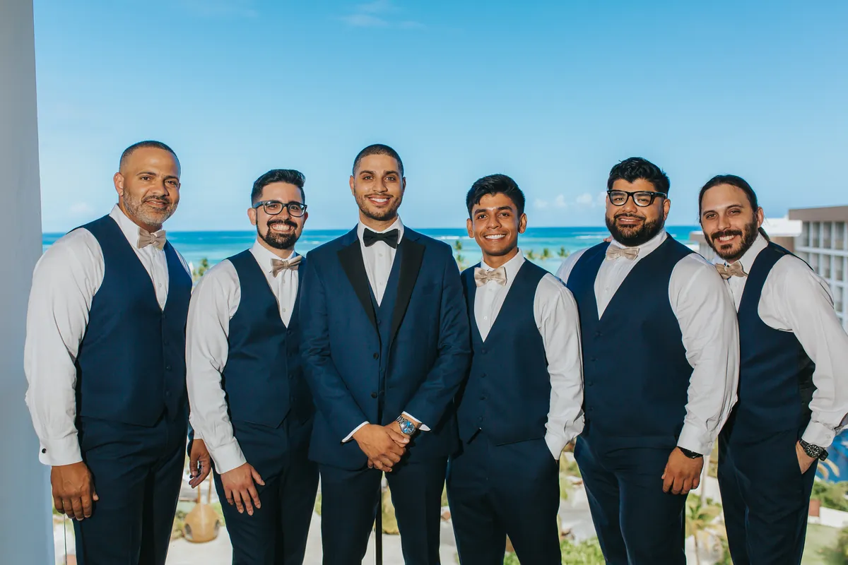 Novio con sus padrinos en un balcón frente al mar