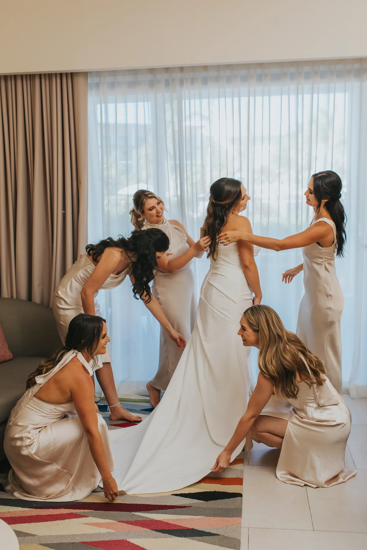 Bridesmaids helping the bride arrange her dress train
