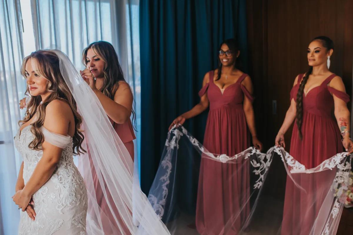 Bridesmaid placing the veil while others hold its lace edge