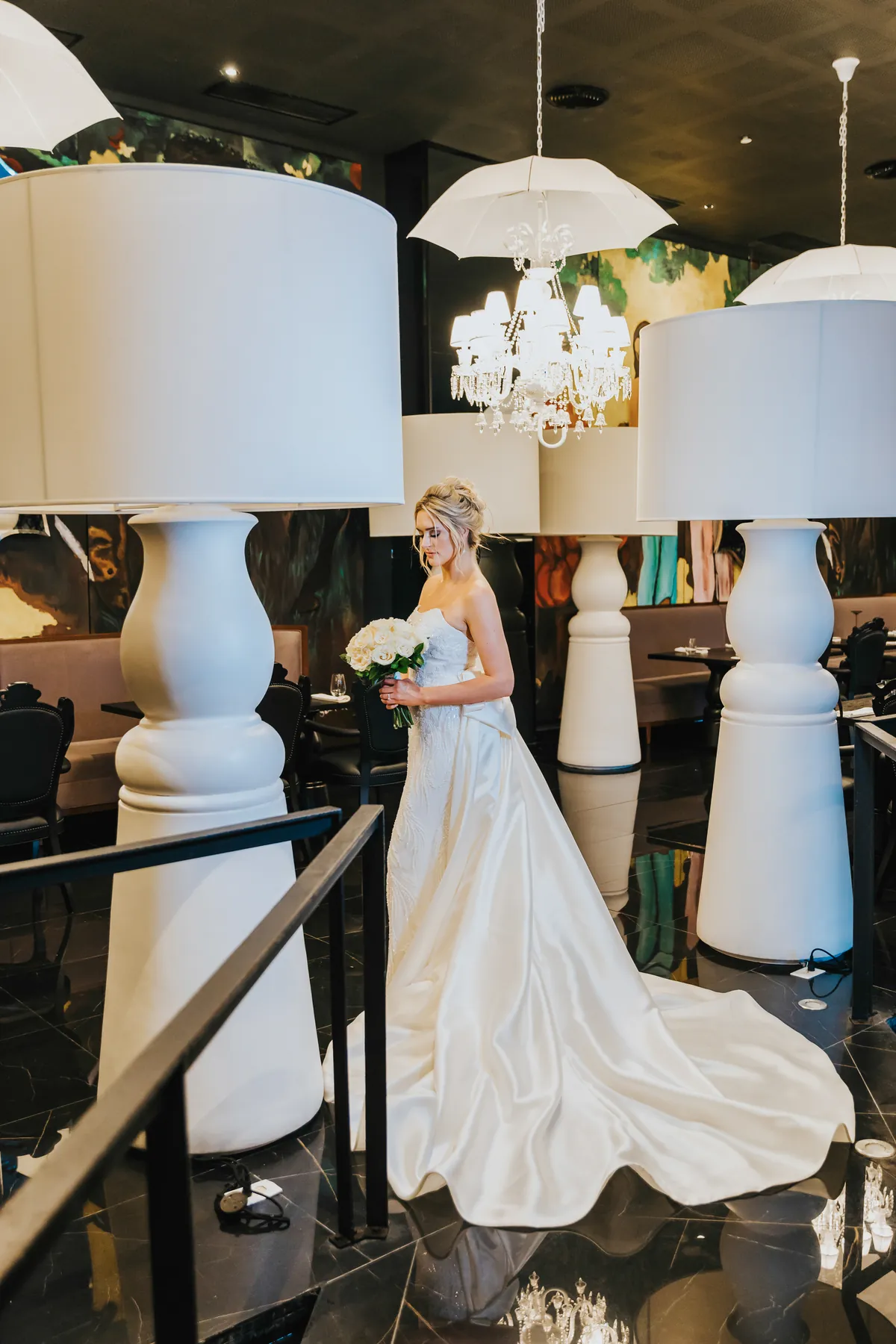 Bride with a long satin train among giant white lamps