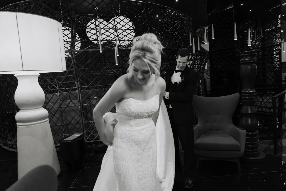 Black and white: the groom fastening the bride's bow