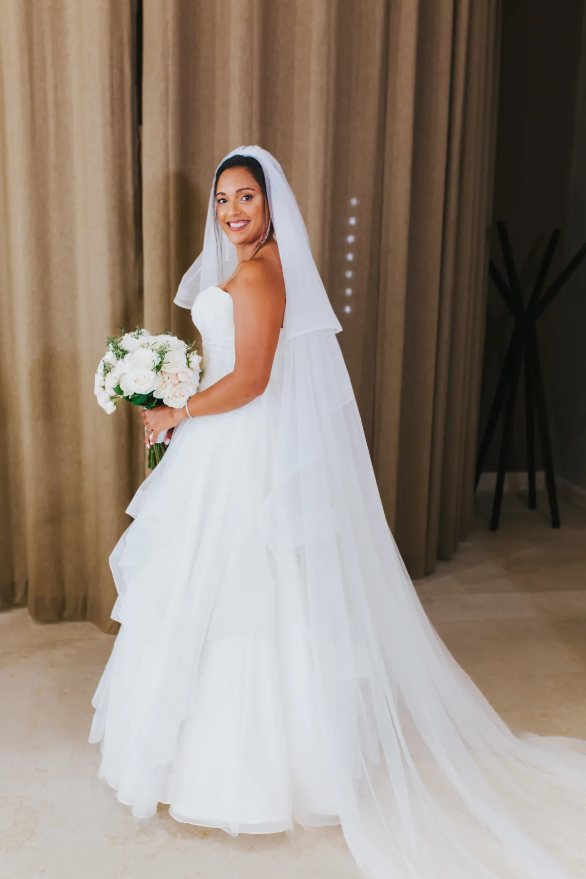 Bride smiling in her wedding dress holding a white bouquet