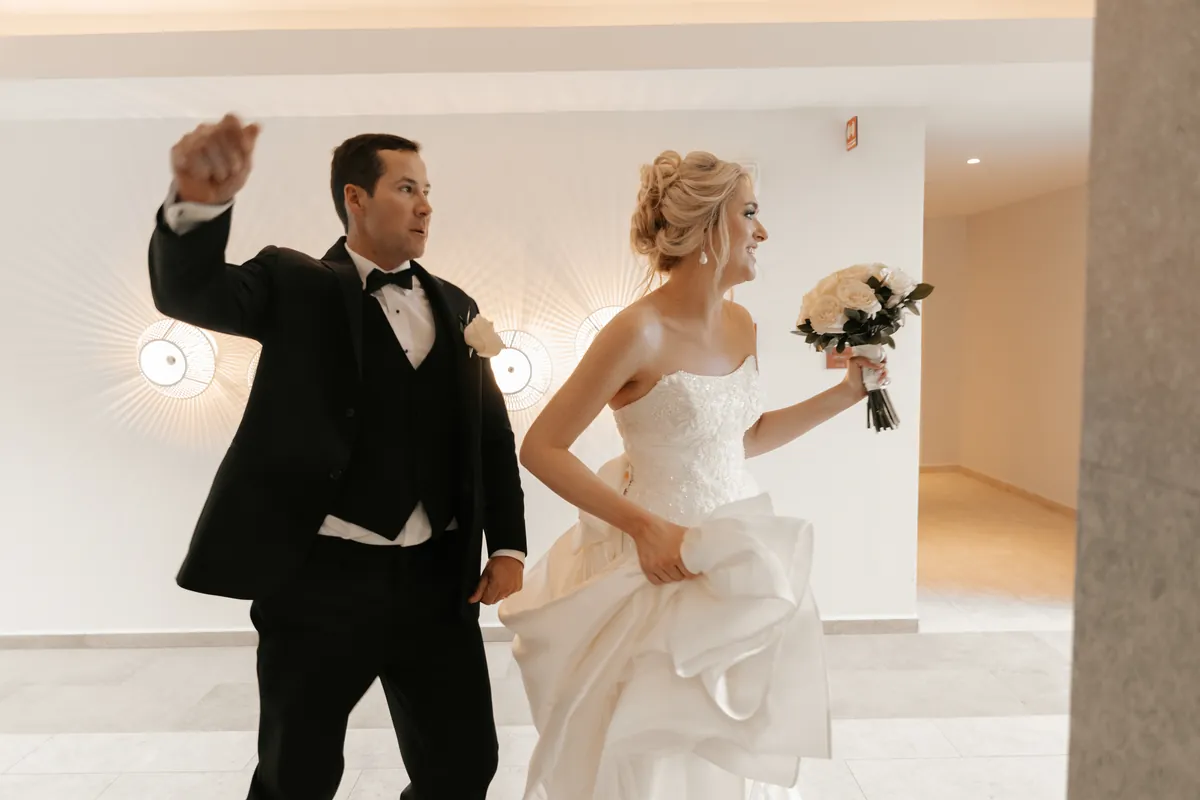 Groom cheering as the bride runs to the celebration holding her train